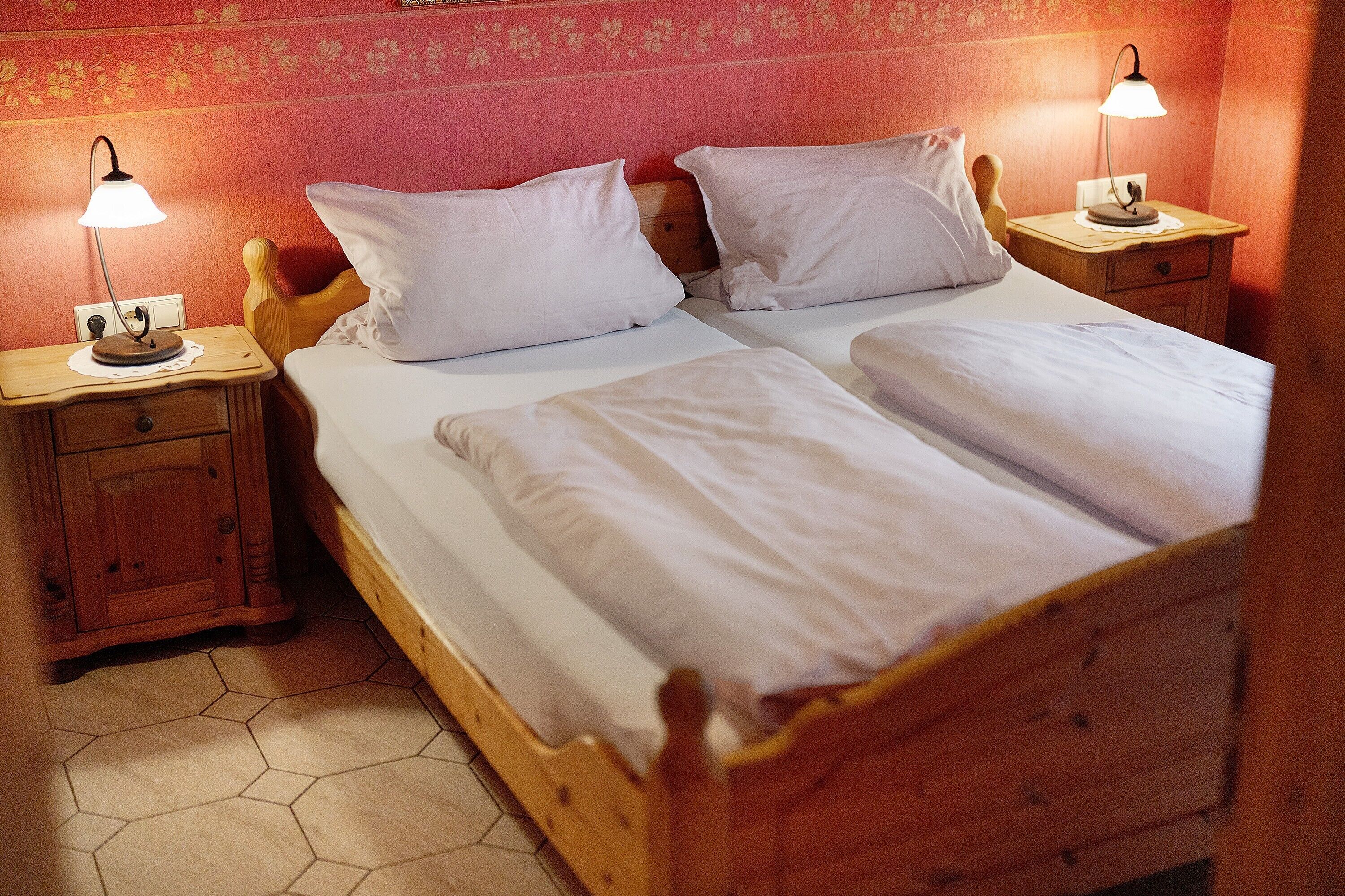Ein Doppelbett mit weißen Leinentüchern, zwei Nachttische mit Lampen und ein Holz-Kopfteil.