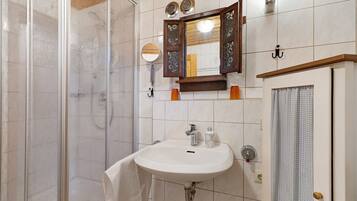 Ein Badezimmer mit Dusche, Waschbecken, Spiegel und Handtuchhalter.