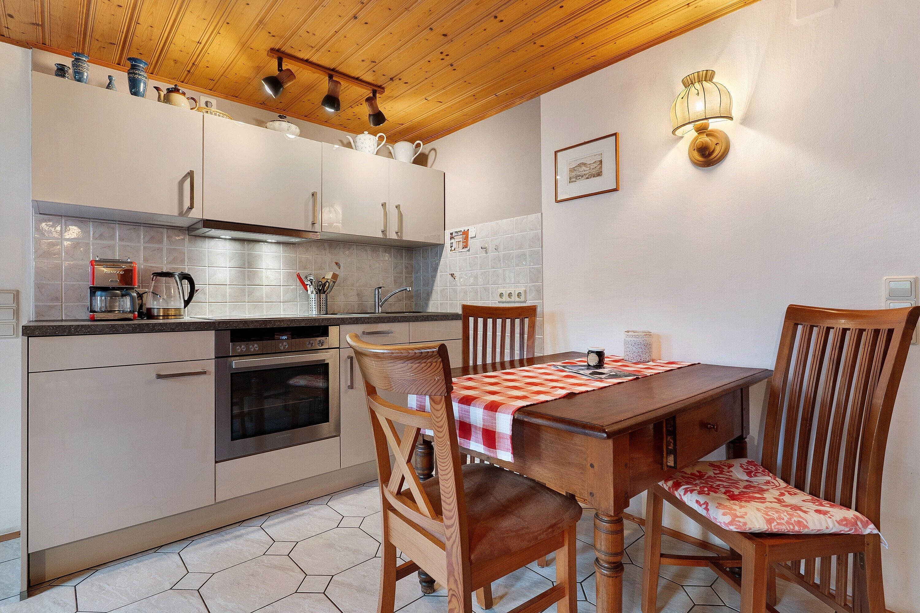 A kitchen with wooden cabinets, a stove, and a dining table with chairs.