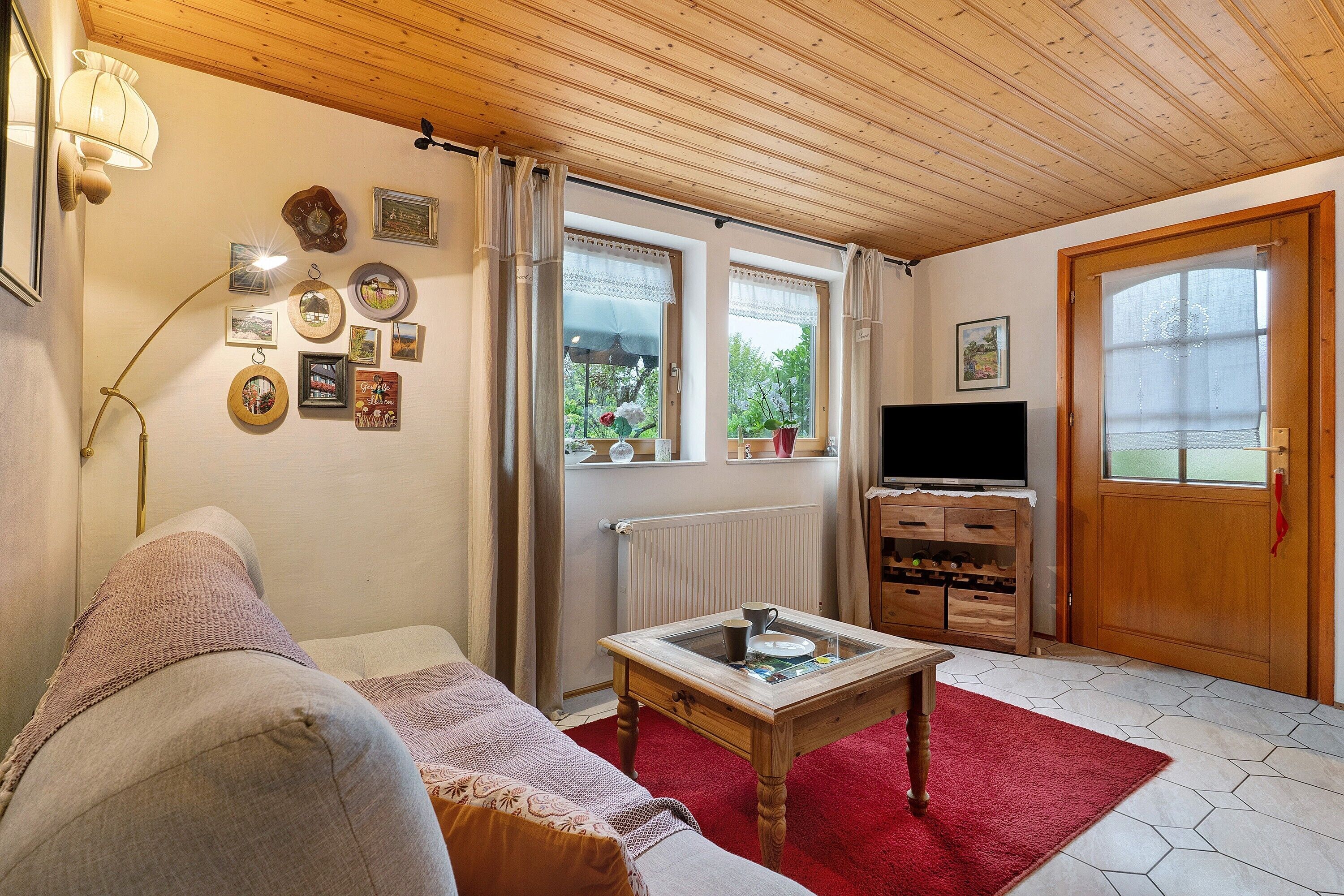 A cozy living room with a sofa, a coffee table, a TV, and a wooden cabinet.