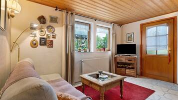 A cozy living room with a sofa, a coffee table, a TV, and a wooden cabinet.