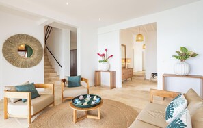 A modern living room with a staircase, a coffee table with cups, and a large mirror. - Les Remparts du Diamant ,spacious 6-bedroom house directly on the Diamond beach (Le Diamant)