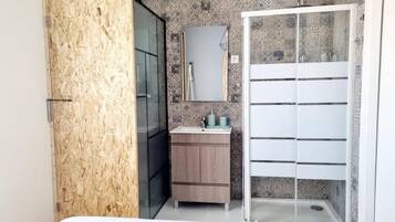 Ein Badezimmer mit einer Holzwand, einem Waschbecken mit Spiegel und einer Duschkabine.
