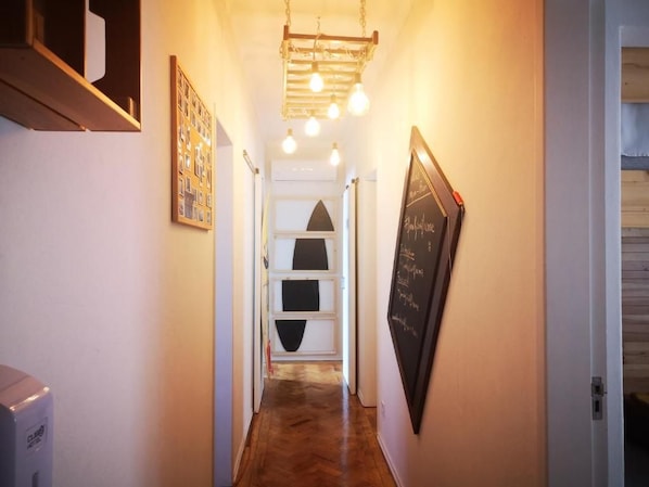 Un pasillo con piso de madera, una pizarra con escritura y un cuadro enmarcado en la pared.