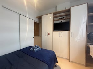 Ein Schlafzimmer mit Bett, Kleiderschrank und Fernseher.
