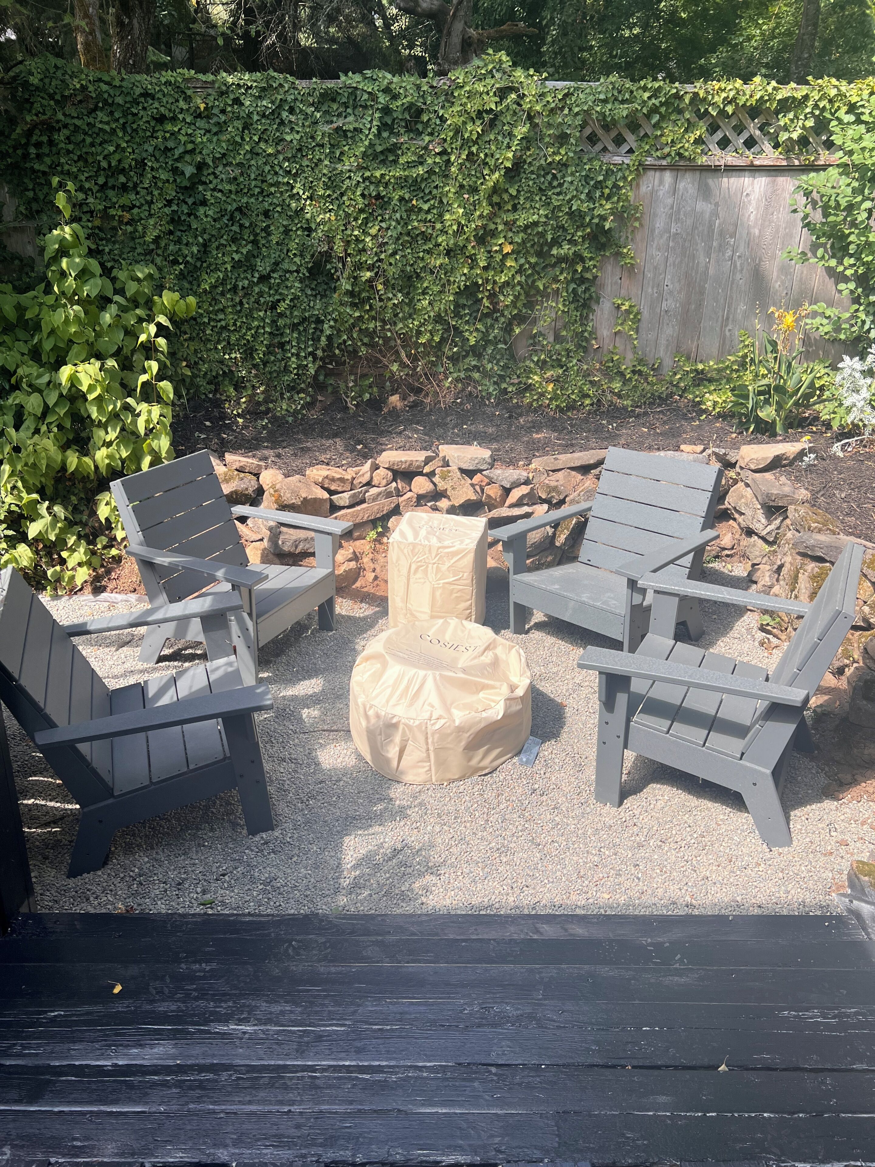 Een terras met Adirondack-stoelen en een afgedekte poef.