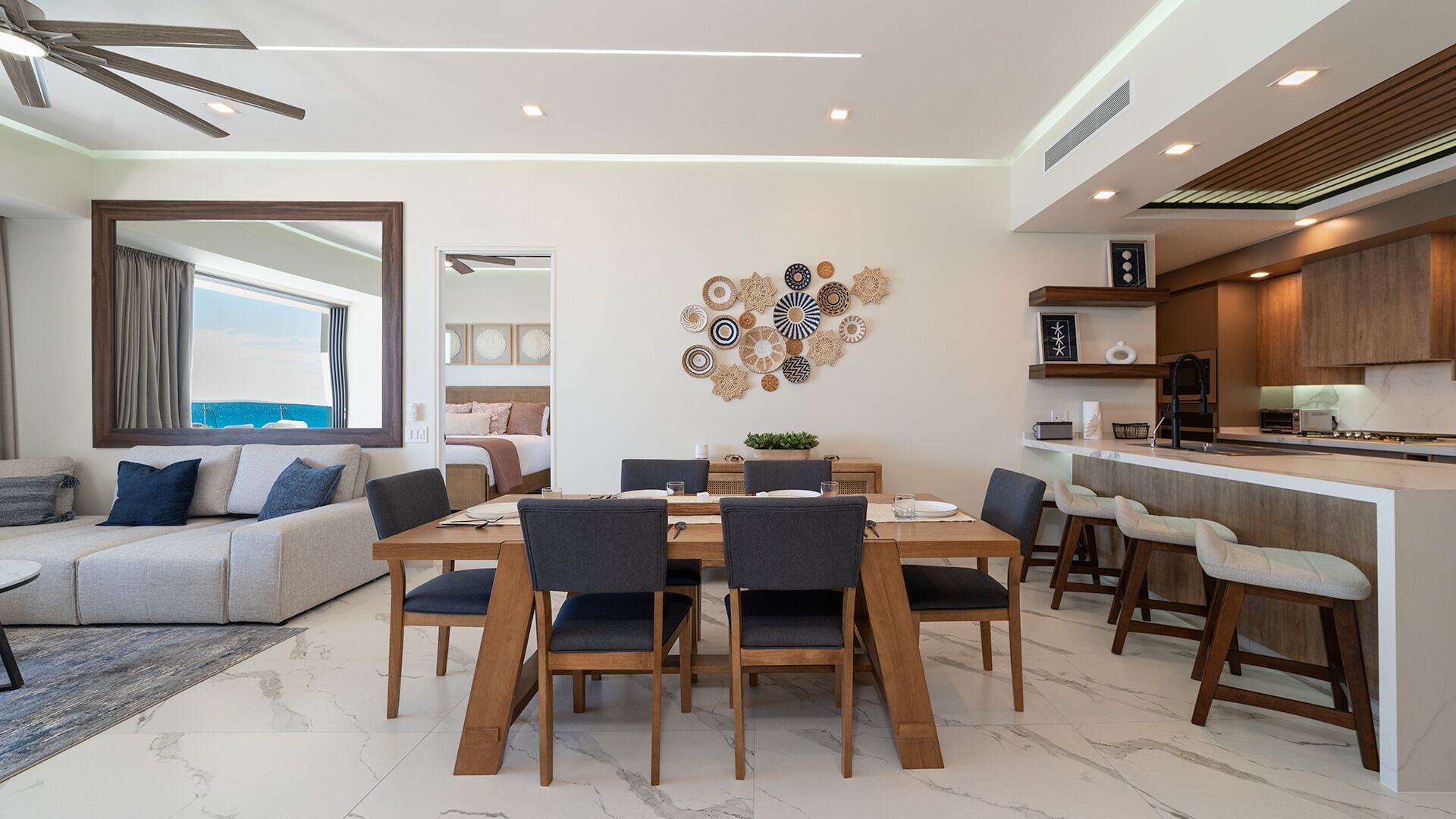 Una sala de estar moderna con comedor, cocina y vista al mar.