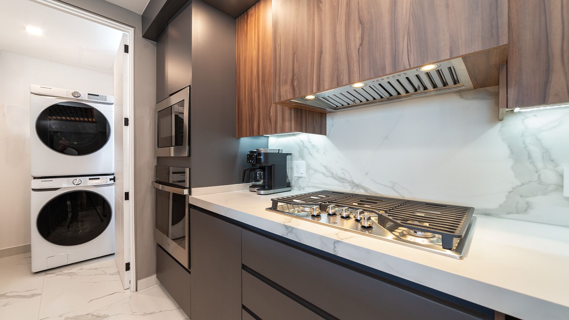 A modern kitchen with built-in appliances, a gas stove, and a coffee maker.