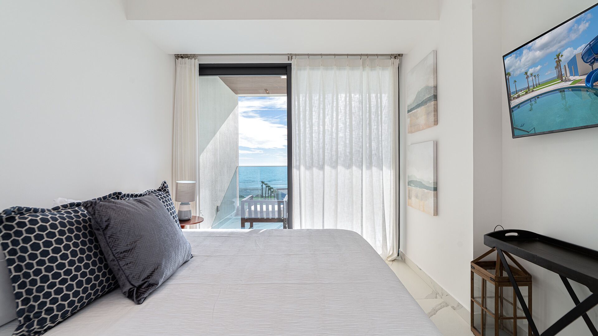 Una habitación de hotel con cama, una mesita, un cuadro y vista al océano.