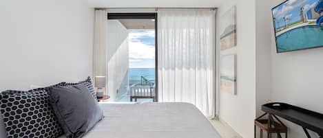 Una habitación de hotel con cama, una mesita, un cuadro y vista al océano.