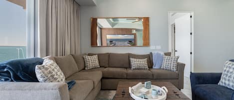 A modern living room with a sectional sofa, a coffee table with a tray, and a large mirror above the sofa.