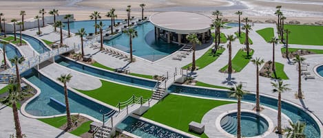 A resort with multiple swimming pools, palm trees, and a beach view.