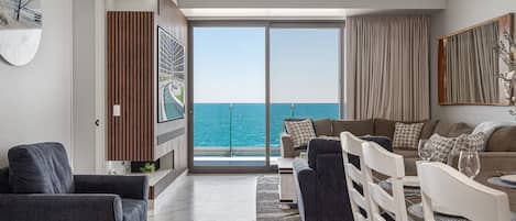 Una sala de estar moderna con vista al mar, un ventilador de techo y un ventanal grande.