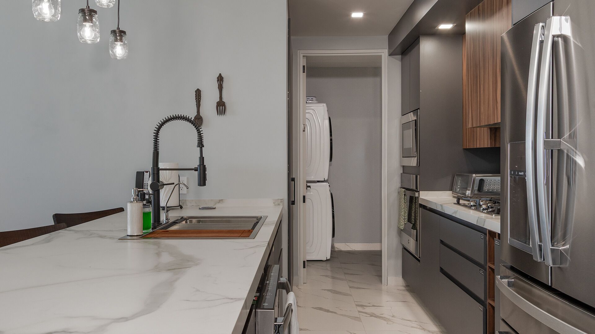 A modern kitchen with a marble countertop, stainless steel appliances, and a built-in oven.