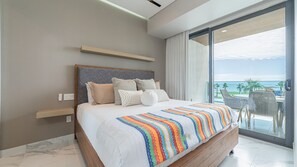 A modern bedroom with a large bed, a view of the ocean, and a balcony with outdoor furniture. - Encantame Soleil (Puerto Peñasco)
