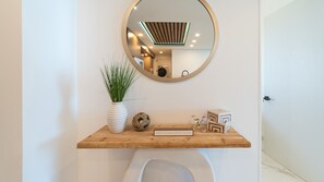 A bathroom vanity with a round mirror, a white vase with green plants, a decorative knot, and a sign that reads 'THIS IS OUR HAPPY PLACE.' - Encantame Soleil (Puerto Peñasco)