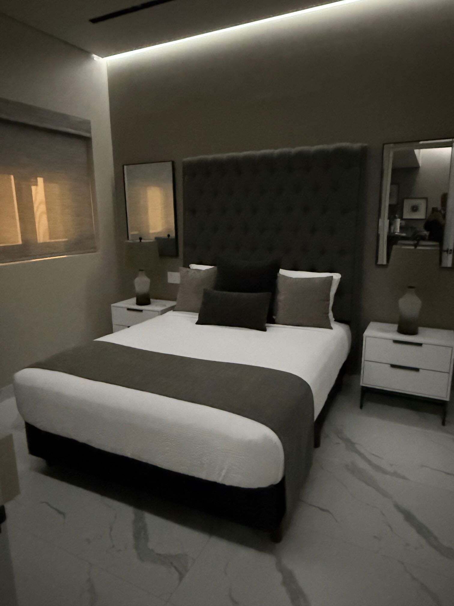 A modern bedroom with a large bed, bedside tables, and a nightstand.