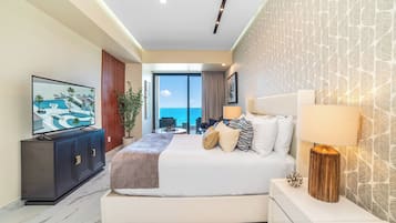 Una habitación de hotel moderna con una cama grande, televisión, vista al mar y un balcón.