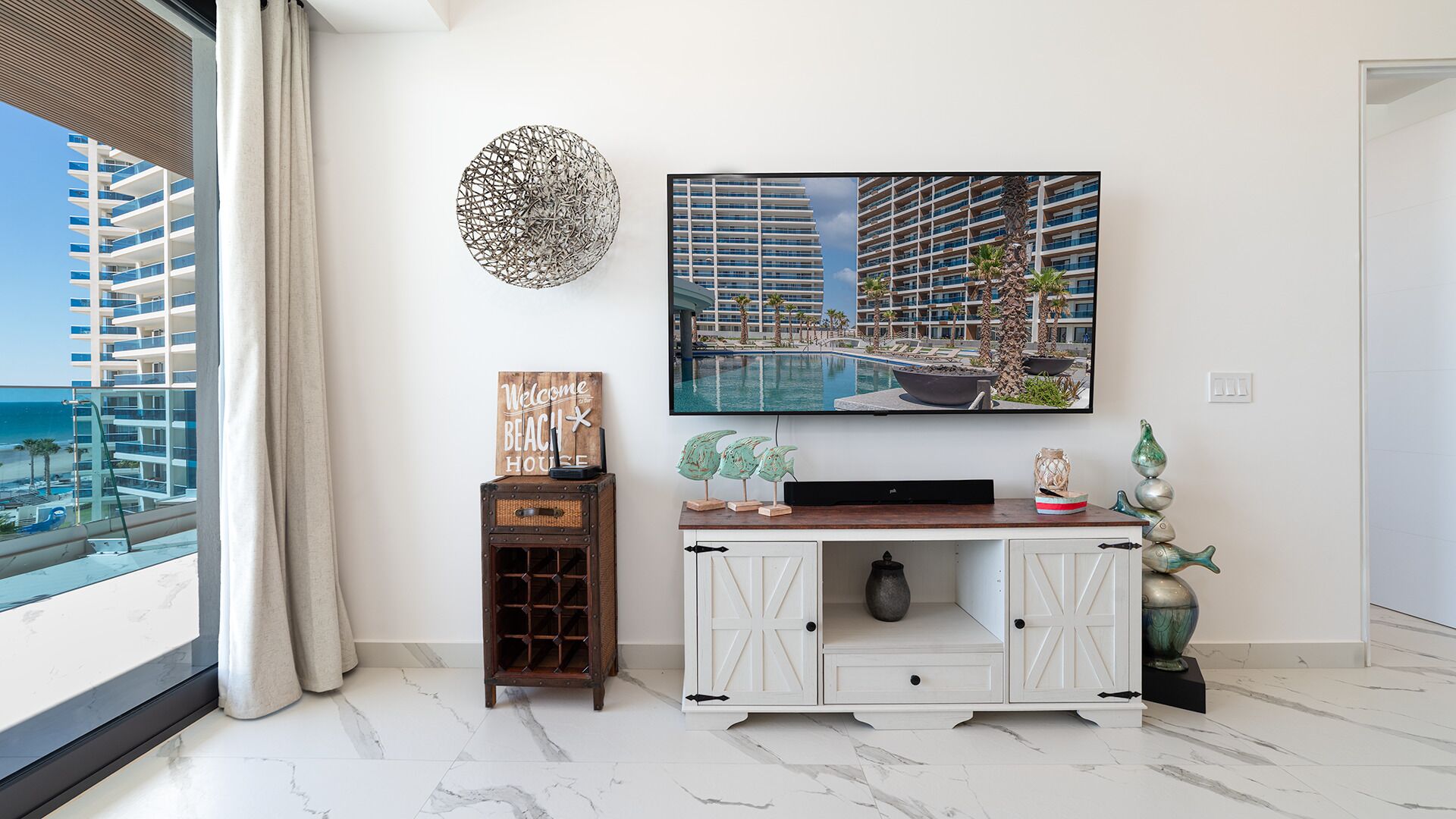 Una sala de estar moderna con un televisor grande, un adorno en la pared y vistas de un hotel.