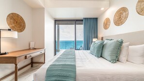 A hotel room with a bed, a desk, and a view of the sea. - Encantame Soleil (Puerto Peñasco)