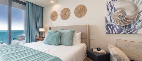 Een hotelkamer met een bed, nachtkastje, lamp en uitzicht op zee.