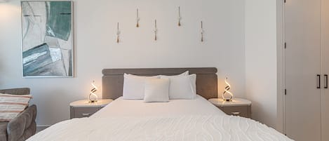 Una camera da letto con un letto grande, due comodini, un'opera d'arte appesa al muro e una porta.