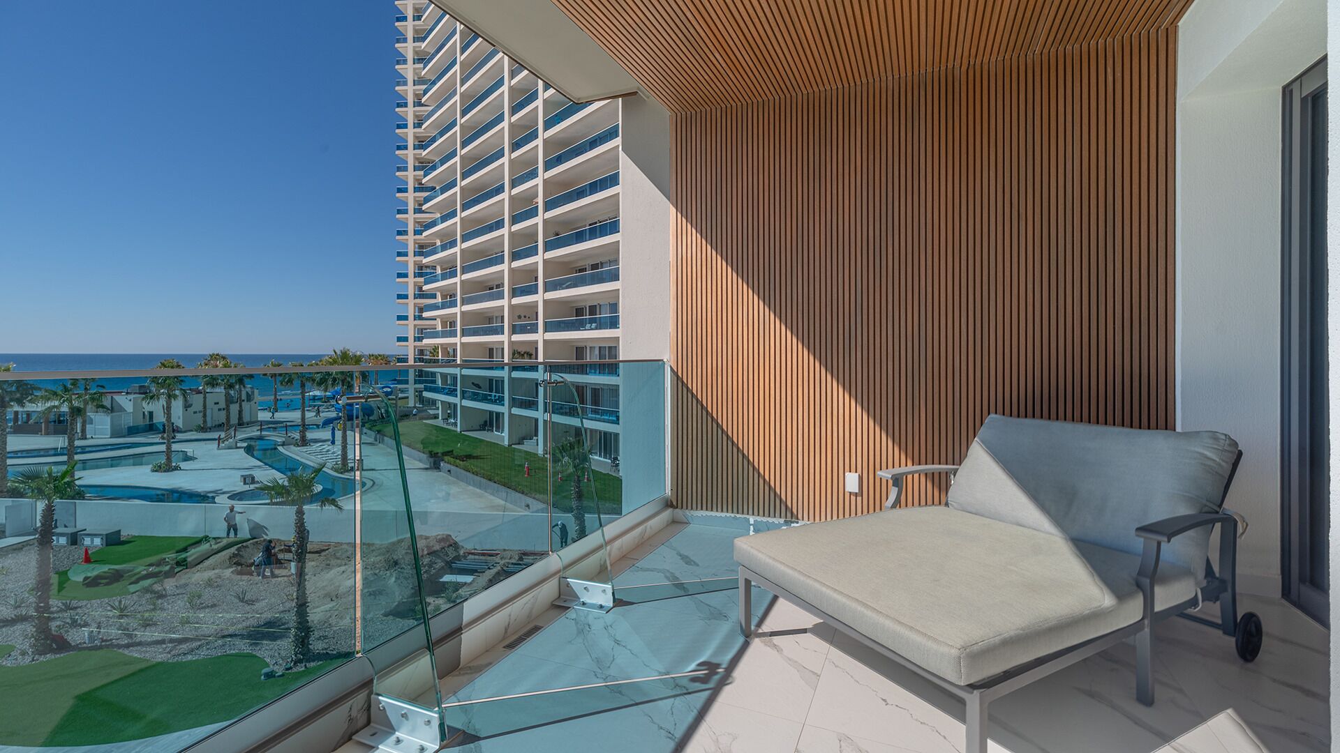 A balcony with a view of a swimming pool and a hotel building.