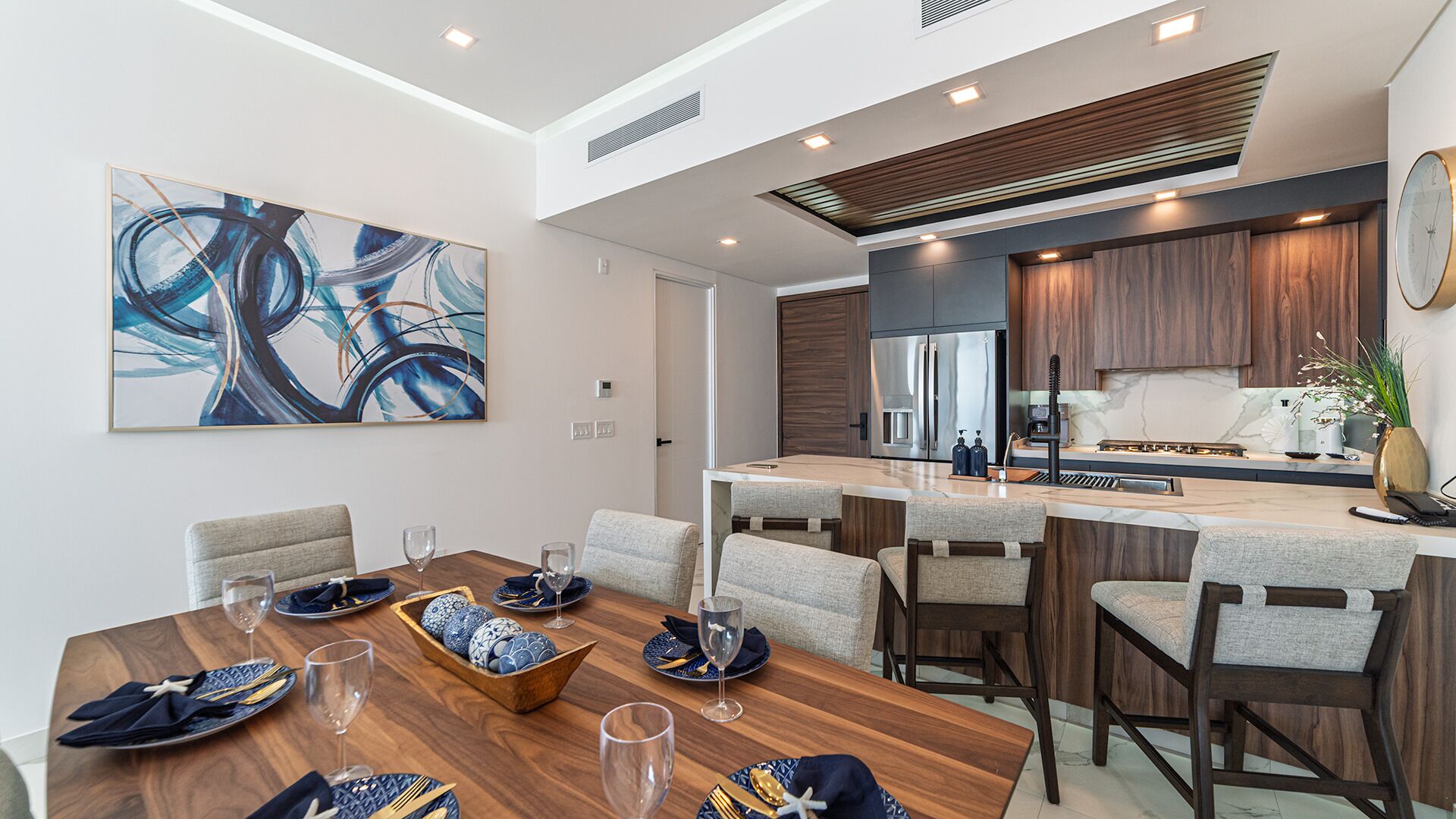 A modern kitchen with a central island, stainless steel appliances, and a dining area with a wooden table and chairs.