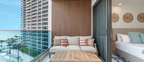 A balcony with a view of a high-rise building and the sea.