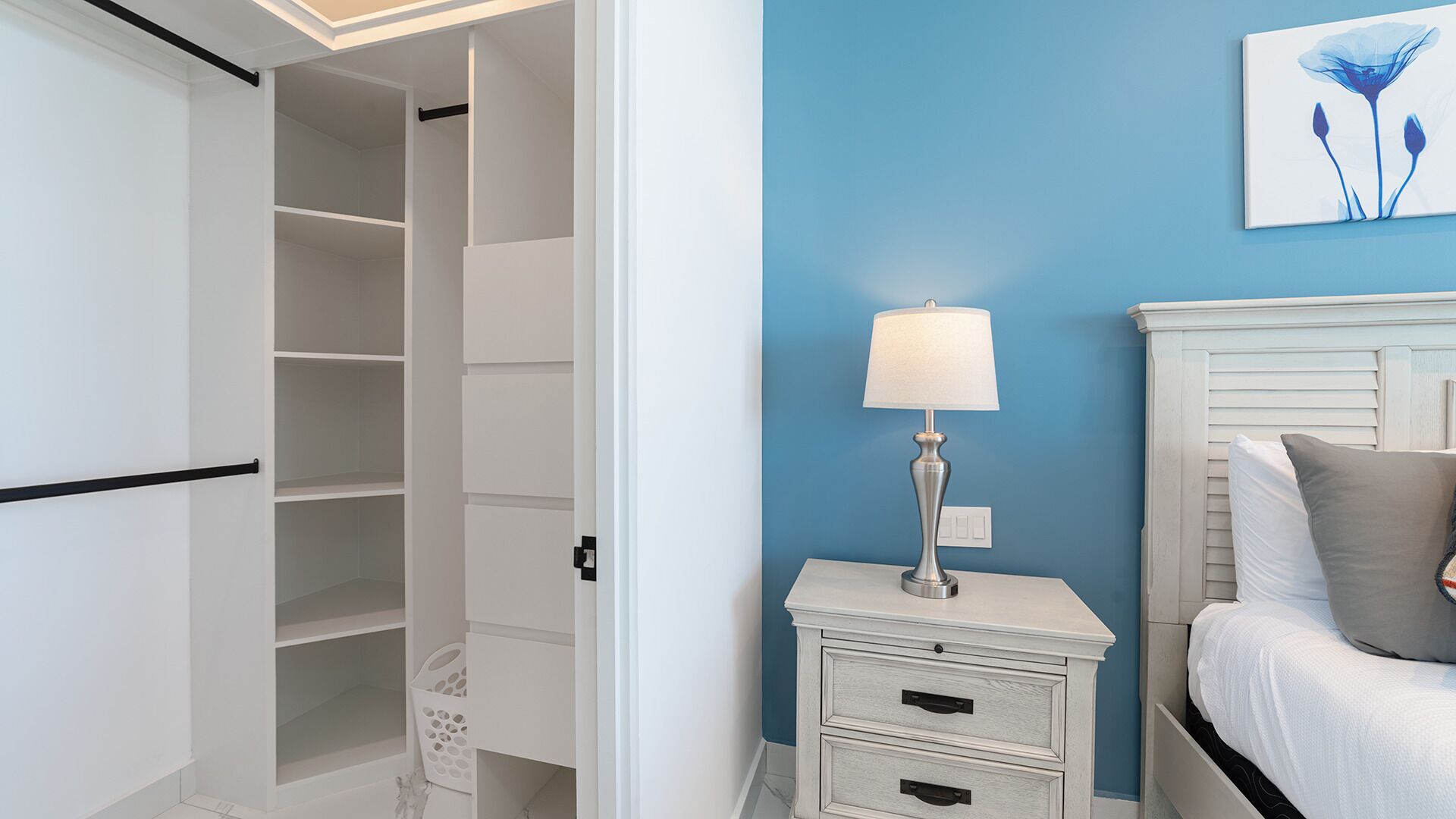 Un dormitorio con cama, mesita de noche con lámpara, cómoda y armario.
