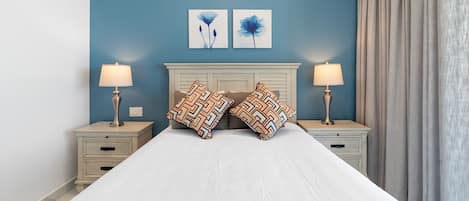 A bed with a white bedspread, two nightstands with lamps, a headboard, and two wall-mounted artworks.