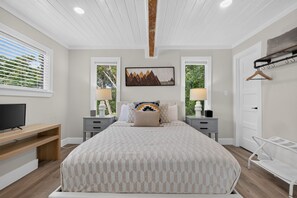 A bedroom with a bed, bedside tables, a TV, a desk, and a chair. - Modern Stunner Walkable to Lake Travis + Views! (Austin)