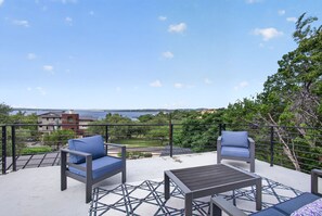 A balcony with two chairs and a table, overlooking a body of water and buildings.