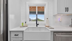 A modern kitchen with a white subway tile backsplash, a window above the sink, and a stainless steel dishwasher. - Modern Stunner Walkable to Lake Travis + Views! (Austin)