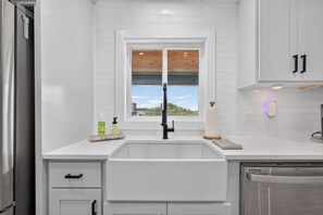 A modern kitchen with a white subway tile backsplash, a window above the sink, and a stainless steel dishwasher. - Modern Stunner Walkable to Lake Travis + Views! (Austin)