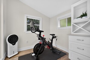 A room with a stationary bike, a fan, and a white cabinet with drawers. - Modern Stunner Walkable to Lake Travis + Views! (Austin)