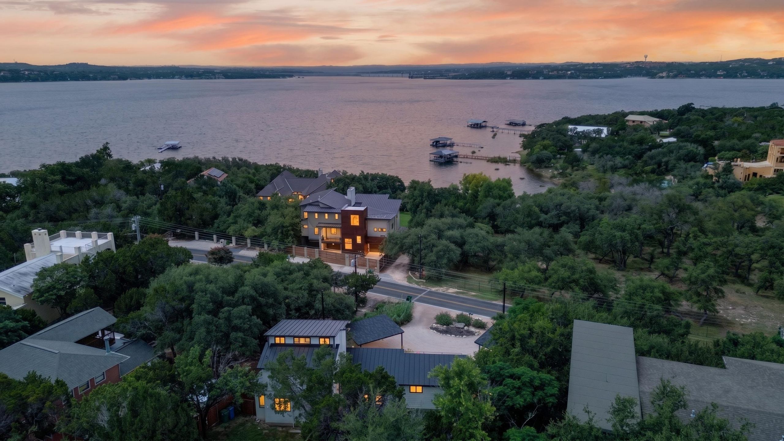 A residential area with houses surrounded by trees, a body of water, and boats.