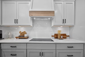 A kitchen with white cabinets, a central island, and a backsplash. - Modern Stunner Walkable to Lake Travis + Views! (Austin)