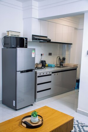 Een moderne keuken met een roestvrijstalen koelkast, een magnetron en een gasfornuis.
