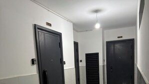 Un pasillo con tres puertas, cada una numerada. El piso está cubierto de baldosas y las paredes son blancas.