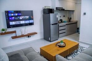 Ett modernt vardagsrum med en platt-TV som är monterad på väggen, ett soffbord i trä och en grå soffa.