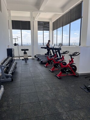 Una palestra con tapis roulant, cyclette e manubri.