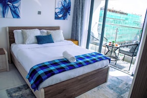 A hotel room with a large bed, a balcony with a table and chairs, and a view of a construction site. - Enjoy a stylish experience at this centrally-located 1-bedroom apartment (Nairobi)