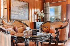 A room with two ornate sofas, a coffee table, a painting, and a vase with flowers. - Beautiful 4-bedroom home, Comfortable, stylish and spacious (Baldwin Park)