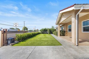 A residential property with a well-maintained lawn, a gated entrance, and a building with a beige facade. - Beautiful 4-bedroom home, Comfortable, stylish and spacious (Baldwin Park)