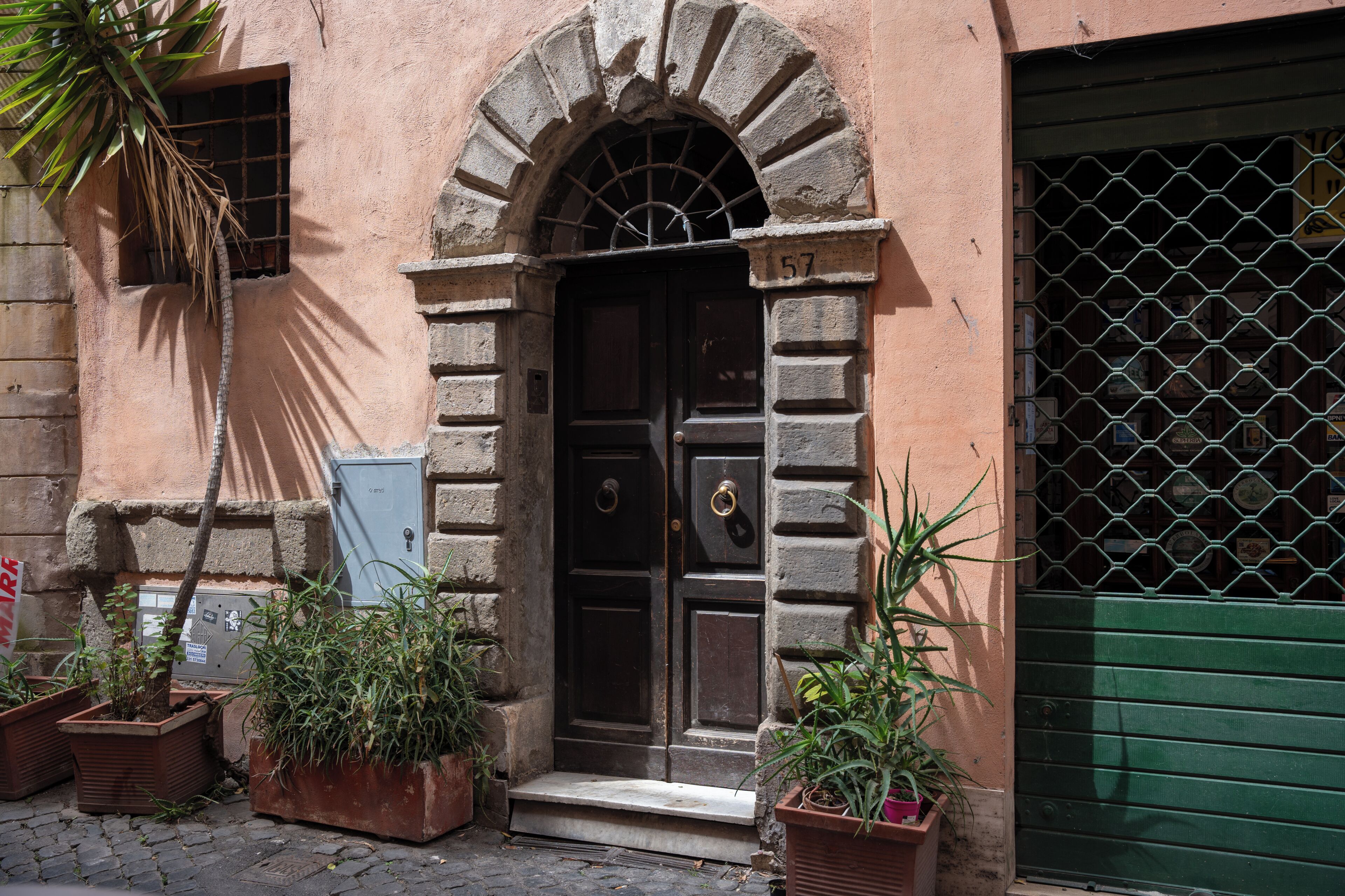 A building with a stone facade, a dark wooden door with a brass knocker, and a green gate.