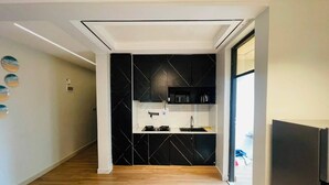 Una cocina moderna con armarios negros, piso de madera y horno empotrado.