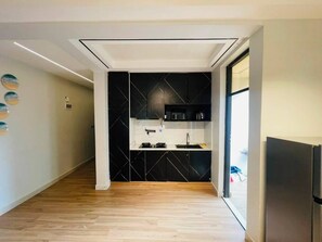 Eine moderne Küche mit schwarzen Schränken, Holzboden und eingebautem Backofen.