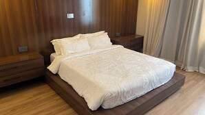 Una cama con colcha blanca en una habitación con paneles de madera y una mesita de noche.