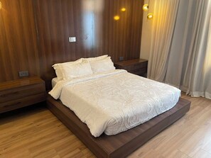 Ein Bett mit weißer Bettdecke in einem Zimmer mit Holzwänden und einem Nachttisch.